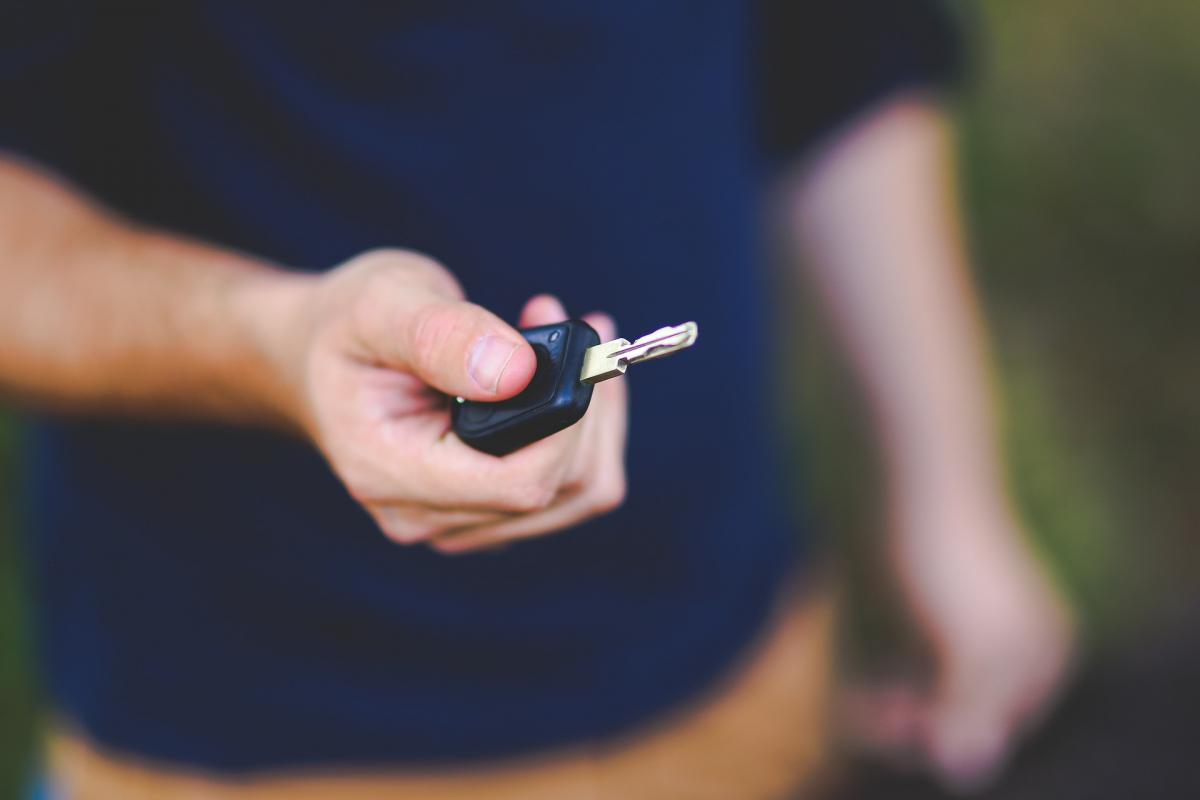 Gros plan sur une main d'homme qui tend une clé de voiture.