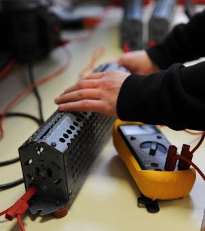 Deux mains de jeune apprenti paramètrent un multimètre.