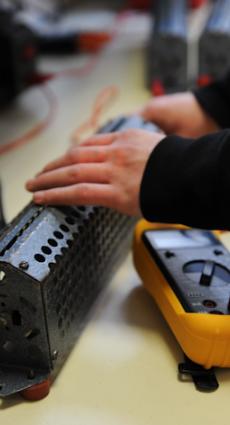 Deux mains de jeune apprenti paramètrent un multimètre.